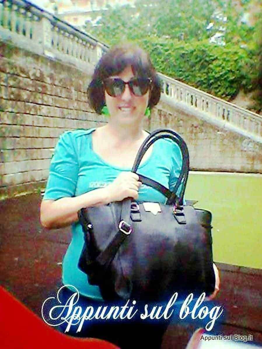 Femmina con occhiali da sole e borsa nera, sorridente all'aperto in giardino, stile casual, sotto il testo "Appunti sul blog".