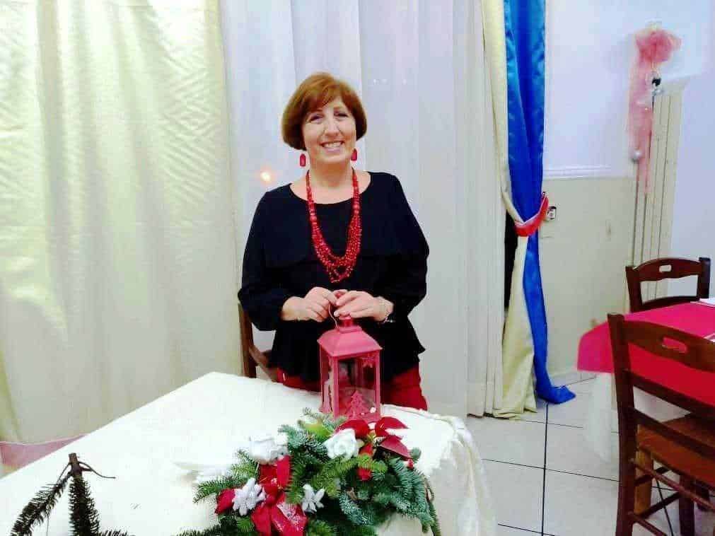 Splendida donna sorridente con decorazioni natalizie e lanterna rossa, atmosfera festiva e accogliente, eventi di Natale, atmosfera calda, ambiente decorato in stile festivo.