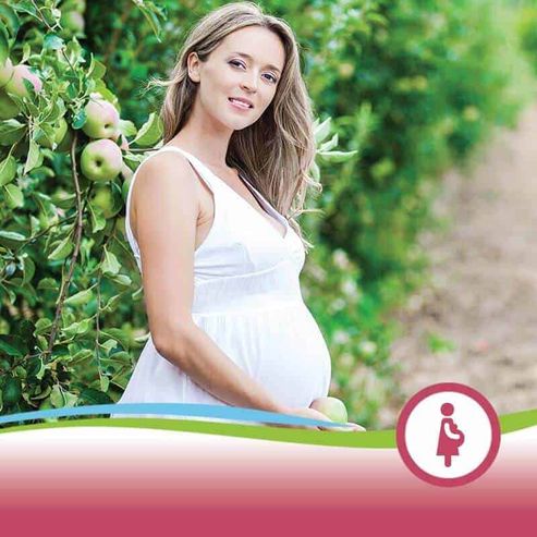Proctosoll Crema Rettale per gravidanza e vita sedentaria: disturbi ed emorroidi 2 Maternità naturale in un frutteto con donna incinta in abito bianco tra mele verdi e foglie rigogliose.