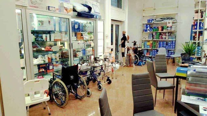 Prodotti ortopedici sanitari Ortopedia Sanitaria MC 2 Sedie e deambulatori in farmacia, con scaffali pieni di prodotti medicinali e dispositivi medicali, ambiente accogliente e ben organizzato per assistere i clienti.