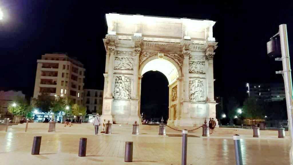 Arch di Trionfo di Parigi illuminato di notte, monumento storico iconico, simbolo di vittoria e gloria, rappresentazione artistica dell'architettura classica con sculture e dettagli ornamentali.