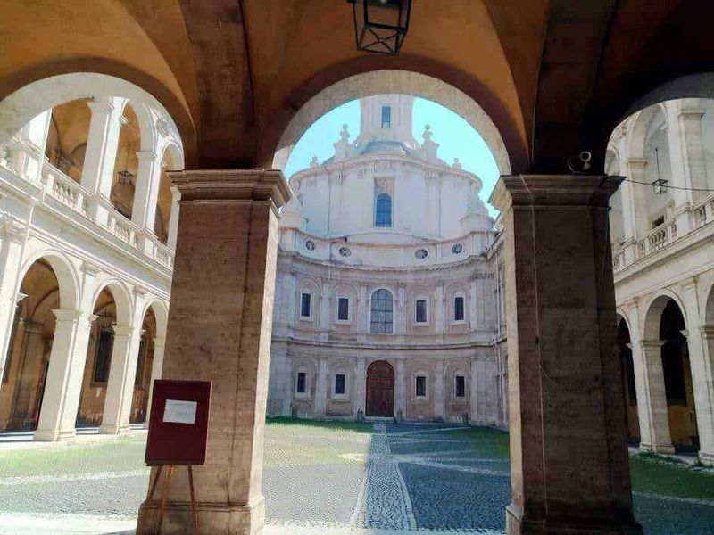 Roma capitale tour in mesi caldi 3 Antica chiesa barocca con portico e cortile interno, architettura storica, elementi decorativi tradizionali, atmosfera affascinante, cultura e storia italiana, luogo di interesse turistico e religioso.