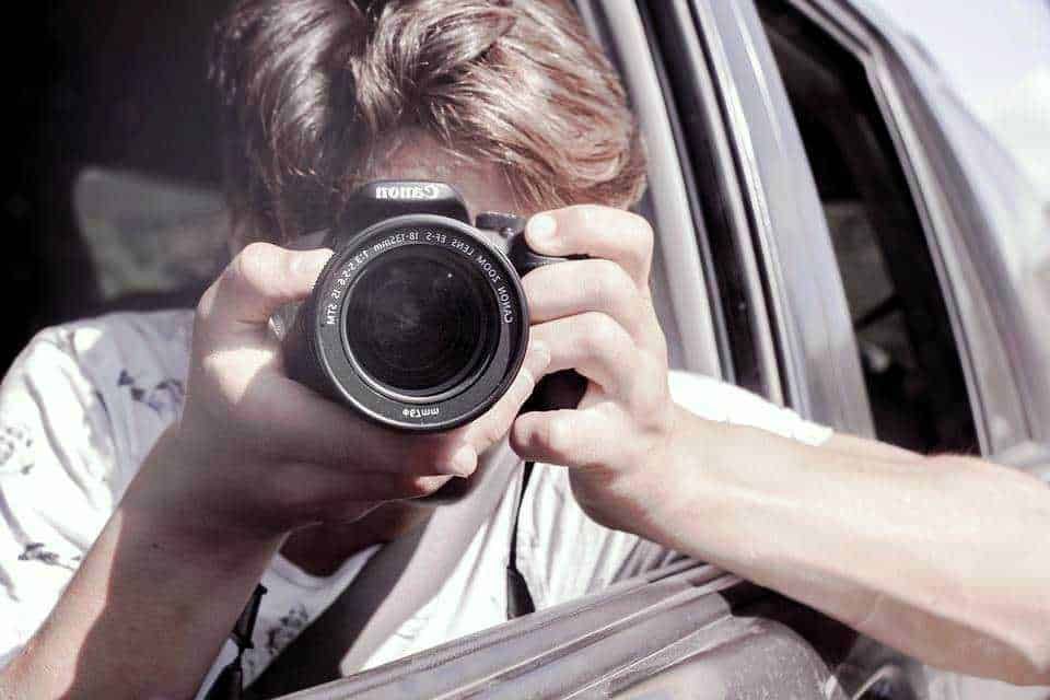 FOTO DI UN RAGAZZO CHE FA UNA SELFIE CON LA MACCHINA FOTOGRAFICA DAL FINESTRA DEL VEICOLO.
