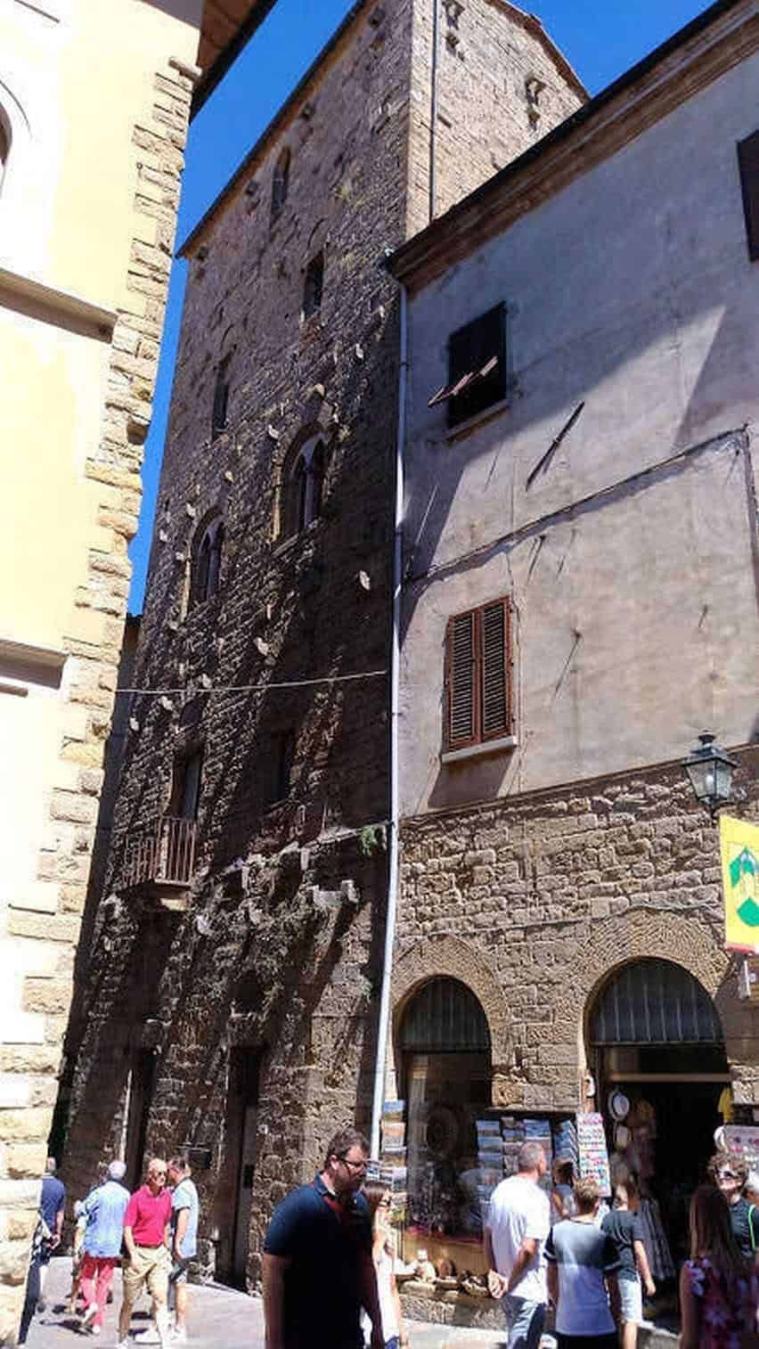 Visita Volterra e i suoi grattacieli. Antico edificio in pietra con archi e finestre in Lucca, Toscana, Italia, centro storico, turisti che passeggiano, stile medievale, attrazione turistica, borghi italiani, architettura storica, cultura italiana.
