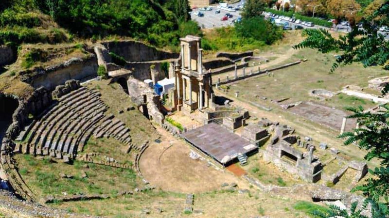 Resti archeologici del teatro antico di Pompei con gradinate e strutture romane ben conservate, situati in un sito storico di grande importanza culturale in Italia.
