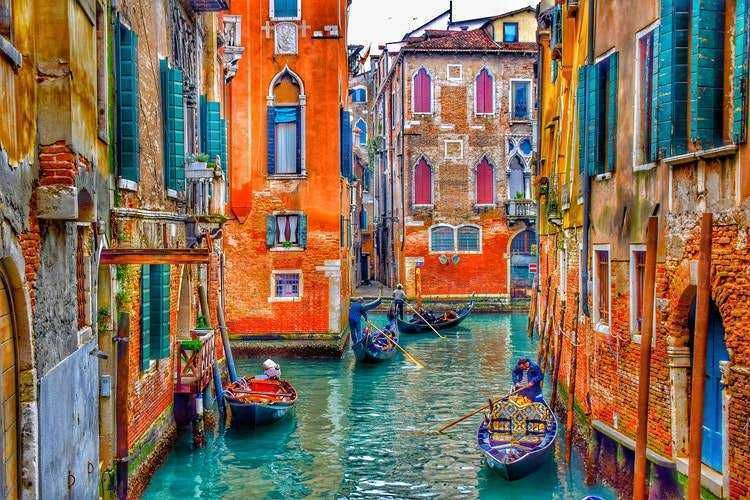 Weekend a Venezia: 13 cose che non potete perdervi! 12 Canali di Venezia con gondole e edifici colorati, scena pittoresca della città vecchia italiana, dettagli delle facciate storiche e atmosfera romantica.