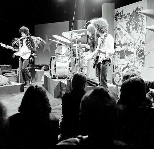 Gruppo musicale dal vivo con strumenti, performance energica su palco, pubblico che guarda con interesse, atmosfera artistica e creativa in un evento culturale.