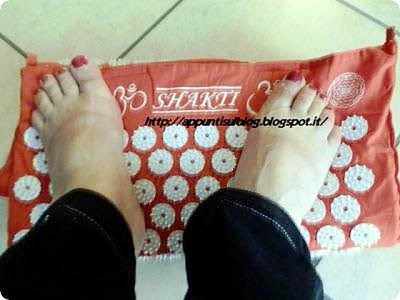 Shakti Mat: tappetino per agopressione e riequilibrio dei 7 chakra 6 Scalda i piedi su un piedi torto in un tappetino arancione con disegni bianchi, ideali per il benessere e il relax. Perfetto per praticare tecniche di rilassamento e cura dei piedi a casa.
