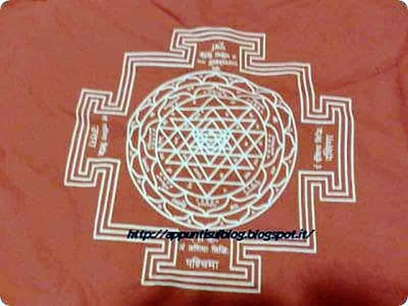 Shakti Mat: tappetino per agopressione e riequilibrio dei 7 chakra 5 Raggi di energia e simboli sacri in un disegno artigianale su tessuto di colore rosso arancio, rappresentando un simbolo spirituale e di meditazione.