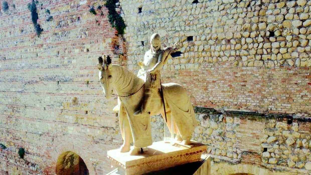 Ponte di Castelvecchio sul fiume Adige a Verona, storico ponte medievale con torre e archi, panorama urbano, zona pedonale lungo il fiume, cielo sereno e riflessi sull'acqua, punti di interesse turistico.