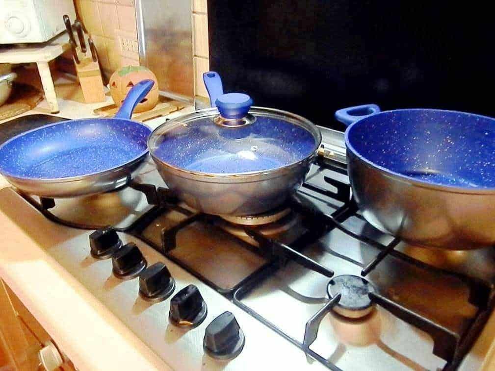 Set di pentole blu con rivestimento antiaderente sul piano cottura a gas in cucina.