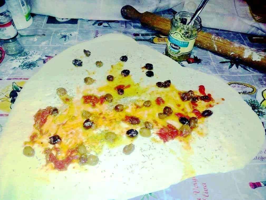 Pomodoro e olive sulla pasta fresca fatta in casa, preparata con ingredienti genuini, all'aperto. Cucina tradizionale italiana con un tocco rustico, perfetta per un pranzo autentico e saporito.