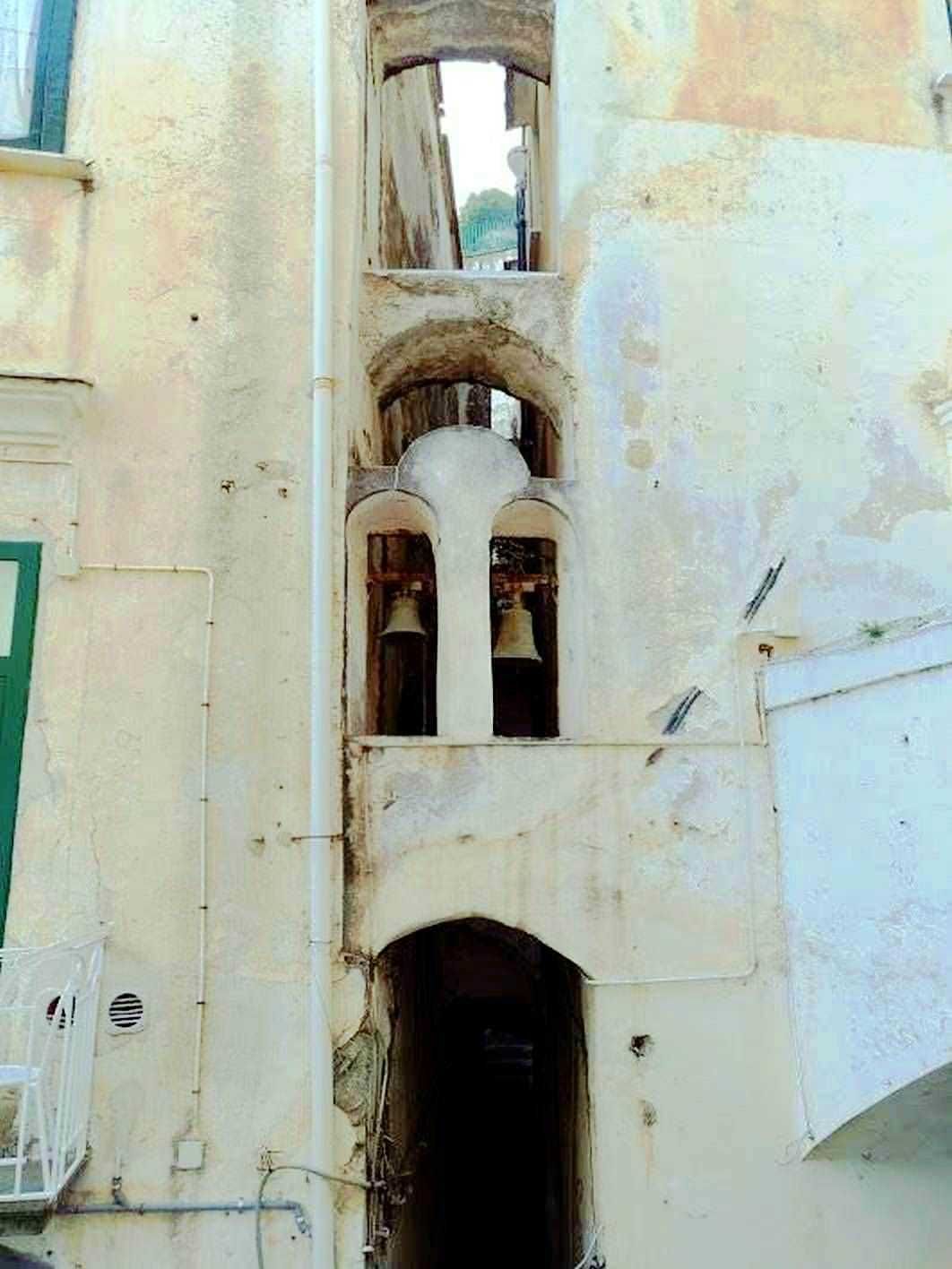Campanile storico in pietra con arcate e finestre su edificio antico