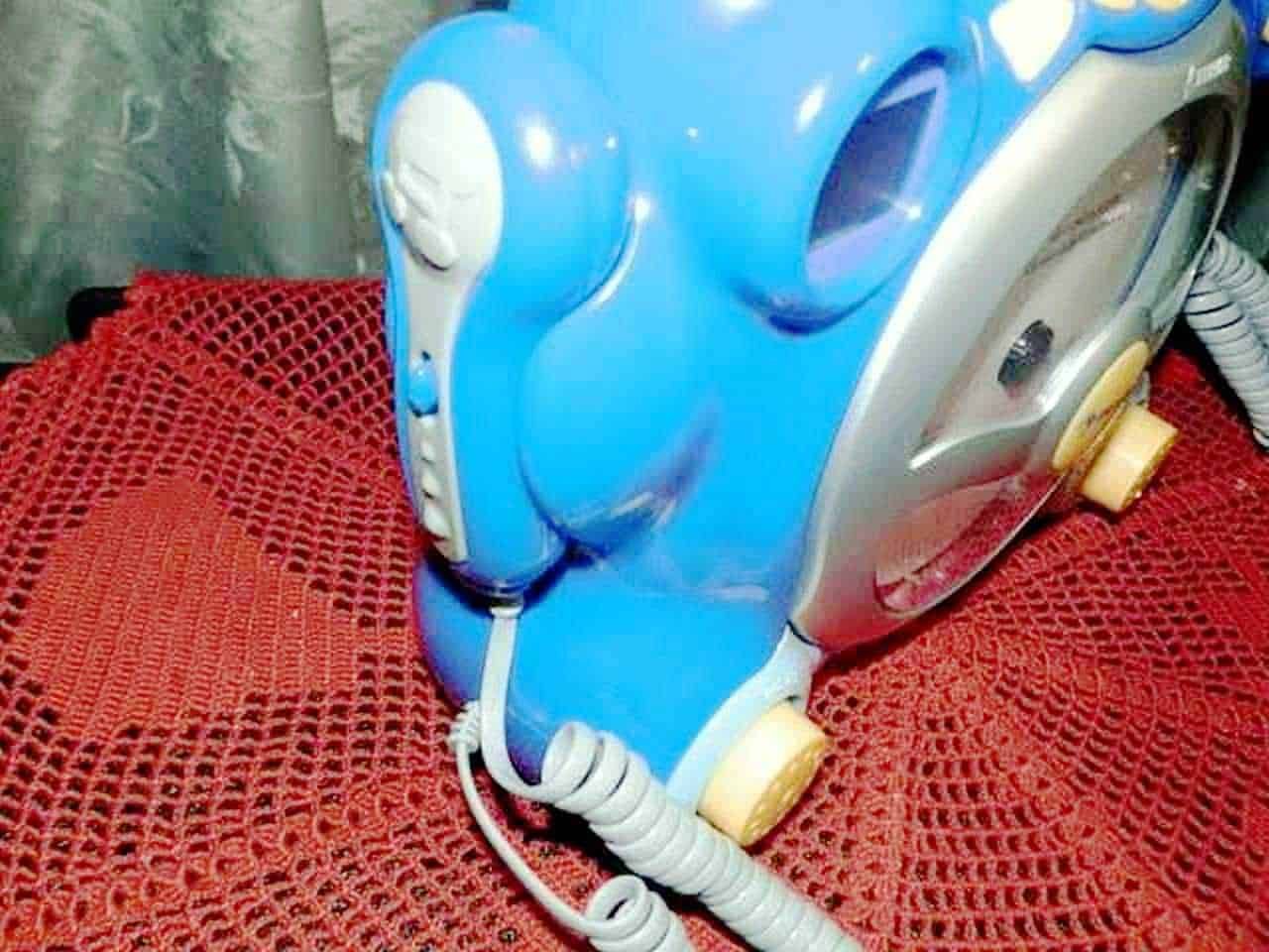 Schermo di una maschera antigas o respiratore per saldatura blu con filtri gialli, appoggiata su un tappeto a maglie rosso. Ideale per protezione respiratoria in ambienti industriali o di saldatura.