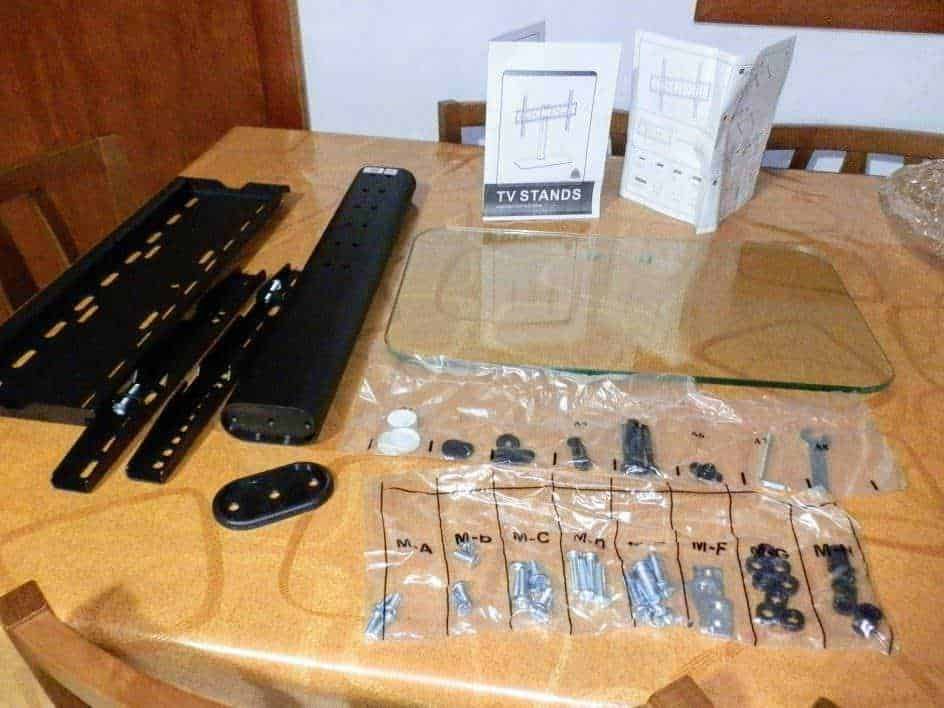 Rilevatore di TV con supporto e accessori, componenti per montaggio, istruzioni e strumenti per assemblare supporto TV in casa. Attrezzi e parti di ricambio per montaggio stabile e sicuro.