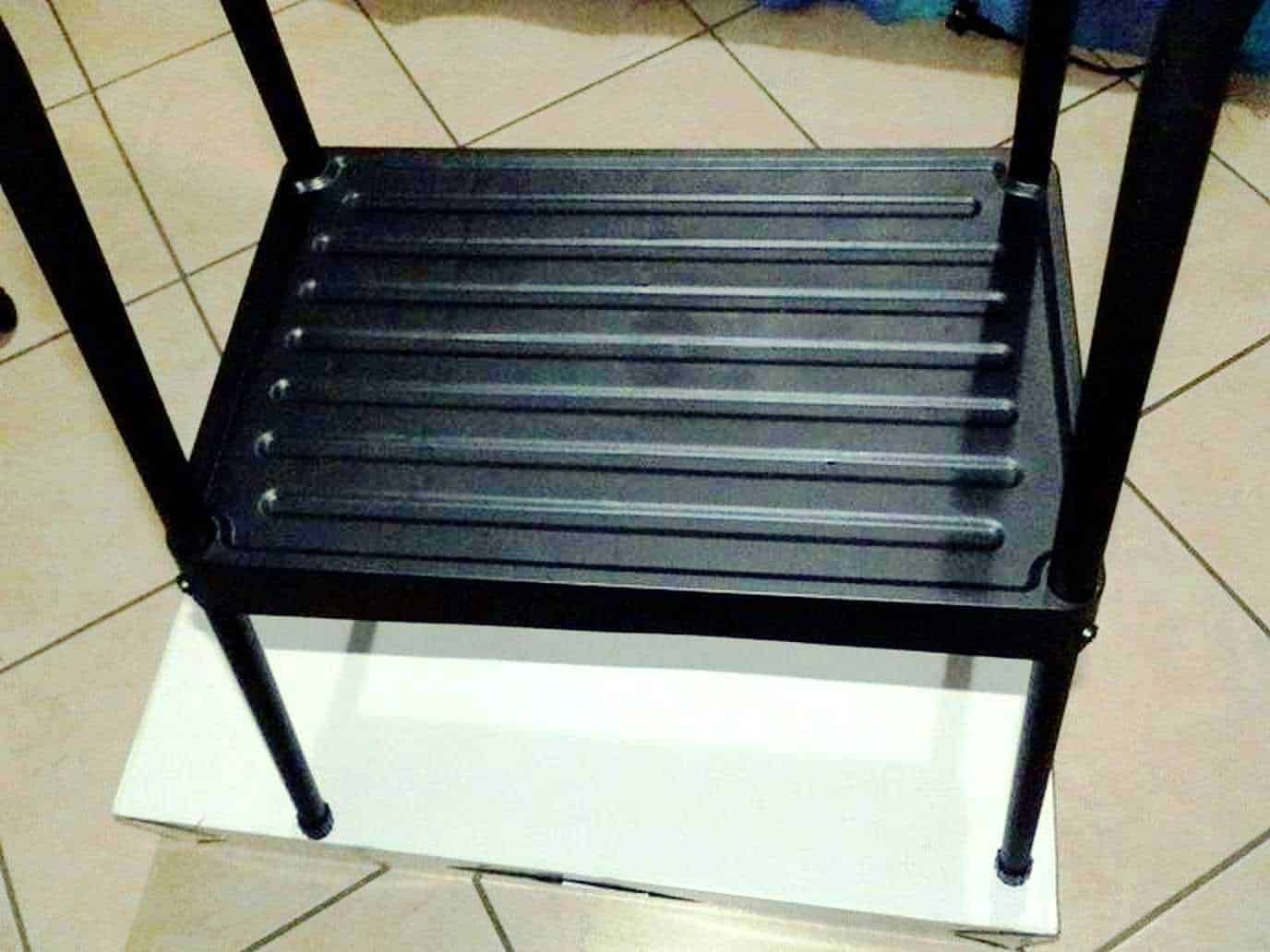 Sgabello nero in metallo con seduta a doghe, struttura robusta e design semplice, ideale per uso interno o esterno, resistente e pratico.