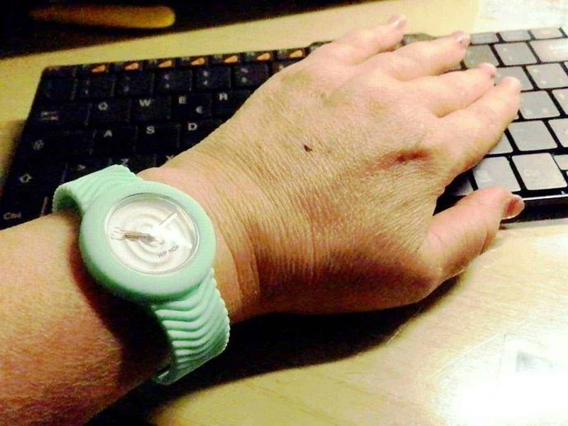 Hip Hop orologi colorati intercambiabili 3 Orologio da polso verde in silicone con quadrante bianco e lancette argentate, indossato su un polso di una mano che sfiora una tastiera di computer, apparentemente in ambiente di lavoro o studio.