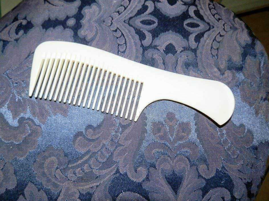 Combs for hair, white plastic detangling comb on blue floral fabric background, hair grooming accessories, hair care tools, personal grooming products.
