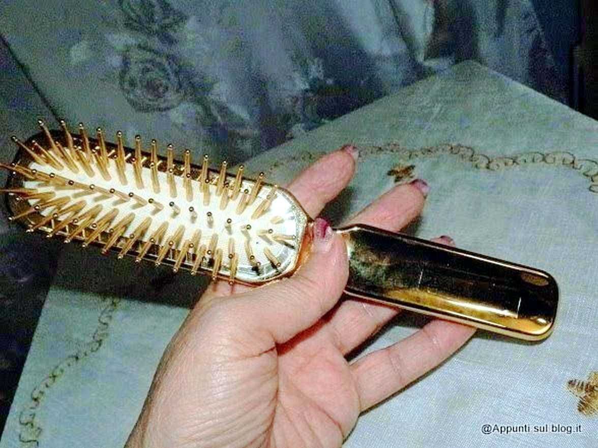 Spazzola per capelli dorata con spilli metallici, in mano, su tessuto colorato, accessorio di bellezza elegante, strumenti per capelli di lusso, cura dei capelli, styling femminile, beauty & haircare.