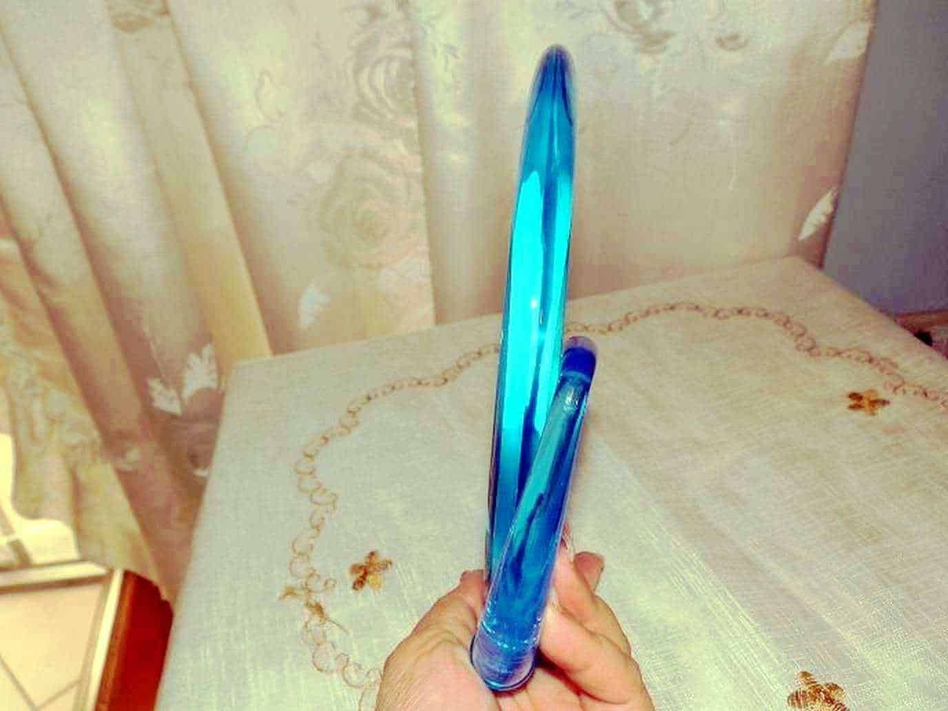 Luce blu fluorescente in un bicchiere di vetro trasparente tenuto in mano.