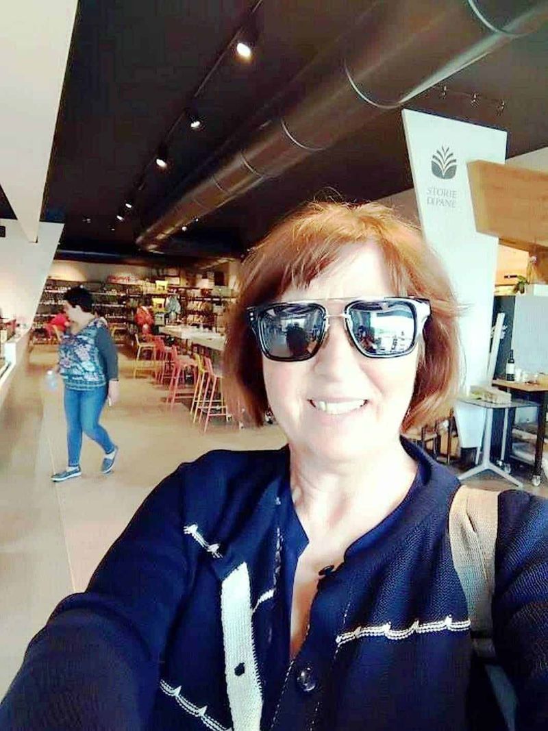 Monte Gelbison e Vallo della Lucania 5 Elegante donna con occhiali da sole in un caffè moderno, sorriso allegro, atmosfera accogliente e design contemporaneo; il ritratto cattura un momento di relax e stile.