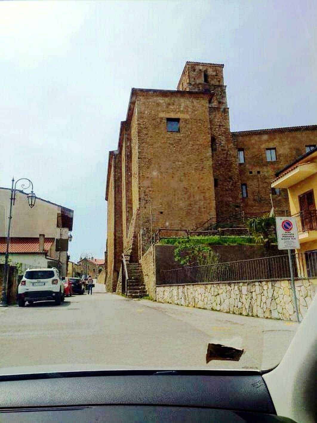Antica torre medievale in pietra elegante e imponente nel cuore di un borgo italiano, con strada affianco e dettagli storici che evidenziano l'arte e la cultura locale.