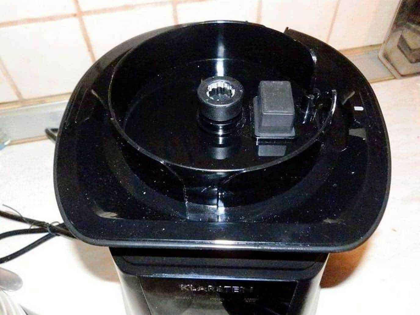 Pixellated black kitchen appliance top view, likely a food processor or blender, on a white countertop. Ideal for home cooking and kitchen gadgets, highlighting modern kitchen equipment.