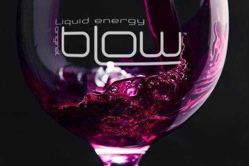 Energia liquida, drink energetico glow con colore viola intenso, focus su vetro con bolle di colore rosa e liquido, design moderno e dinamico, ideale per contenuti su energia e benessere.
