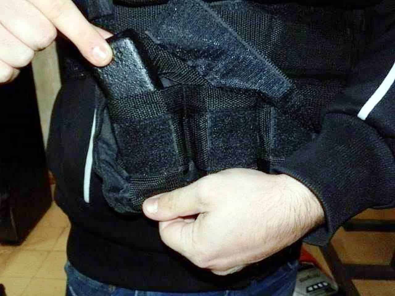 Borsa sportiva nero e grigia in tessuto resistente con tasche interne e zip, uomo che indossa abbigliamento casual, focus sulla apertura della tasca della borsa.