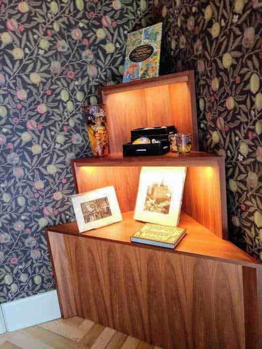 Decorazione di interni con libreria in legno, lampada a LED, fotografie e oggetti d'antiquariato, atmosfera accogliente e vintage, perfetta per arredamento di casa o studio creativo.
