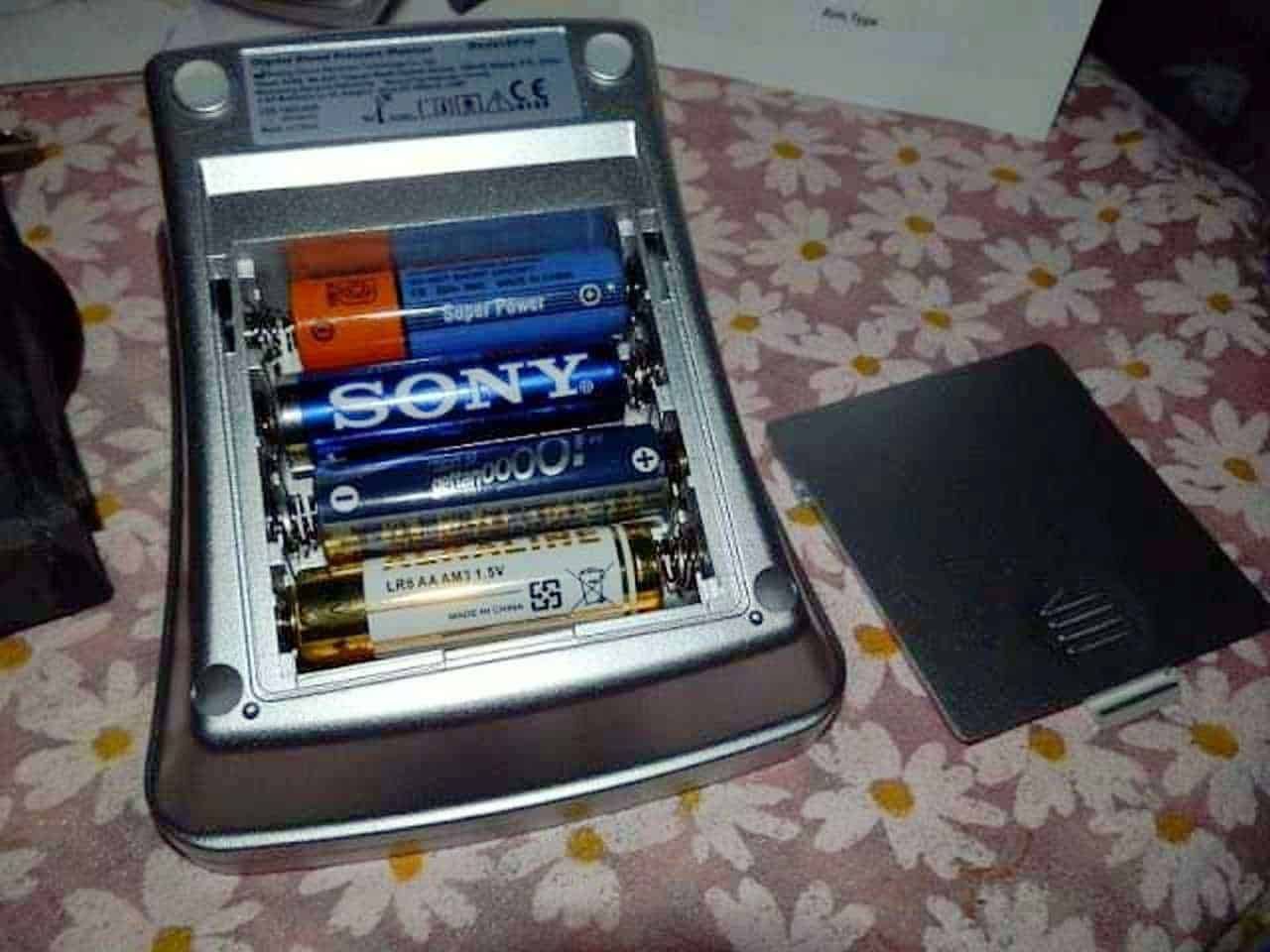 Batteria stilo caricabatterie con batterie Sony e Duracell, vista dall'alto, su tavolo con tovaglia floreale.