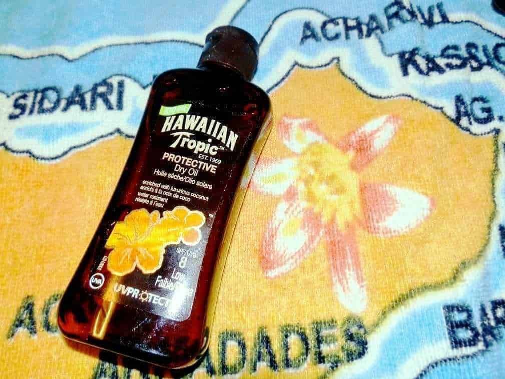 Hawaiian Tropic protezione solare olio secco solare con cocco, protezione UV, ideale per abbronzatura e cura della pelle, foto di un prodotto solare su un tessuto colorato con fiori.