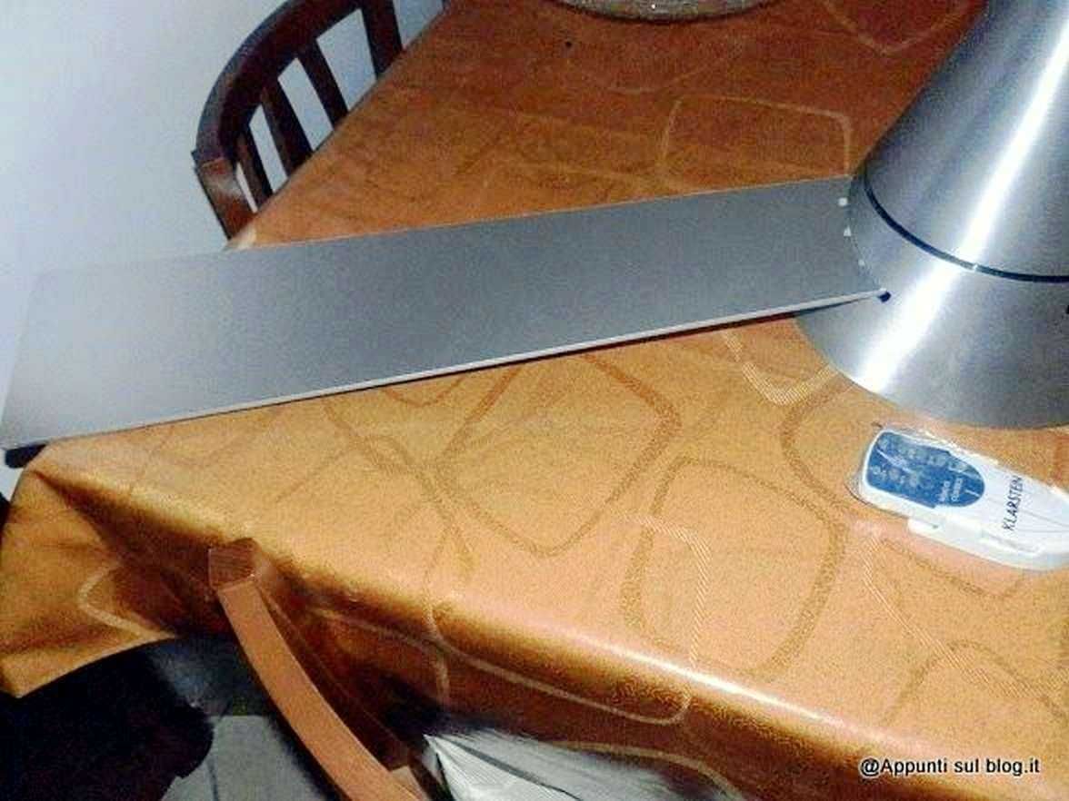 Lama da sega in metallo appoggiata su tavolo con tovaglia arancione e sedie in legno; attrezzi fai-da-te per lavori domestici.