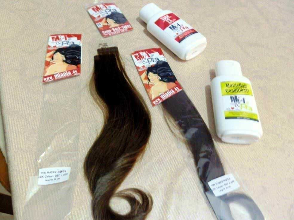 Guaina per extension capelli, tinta castano scuro, con etichette e boccette di prodotti per la cura dei capelli, mentre si prepara un trattamento di restauro e colorazione.