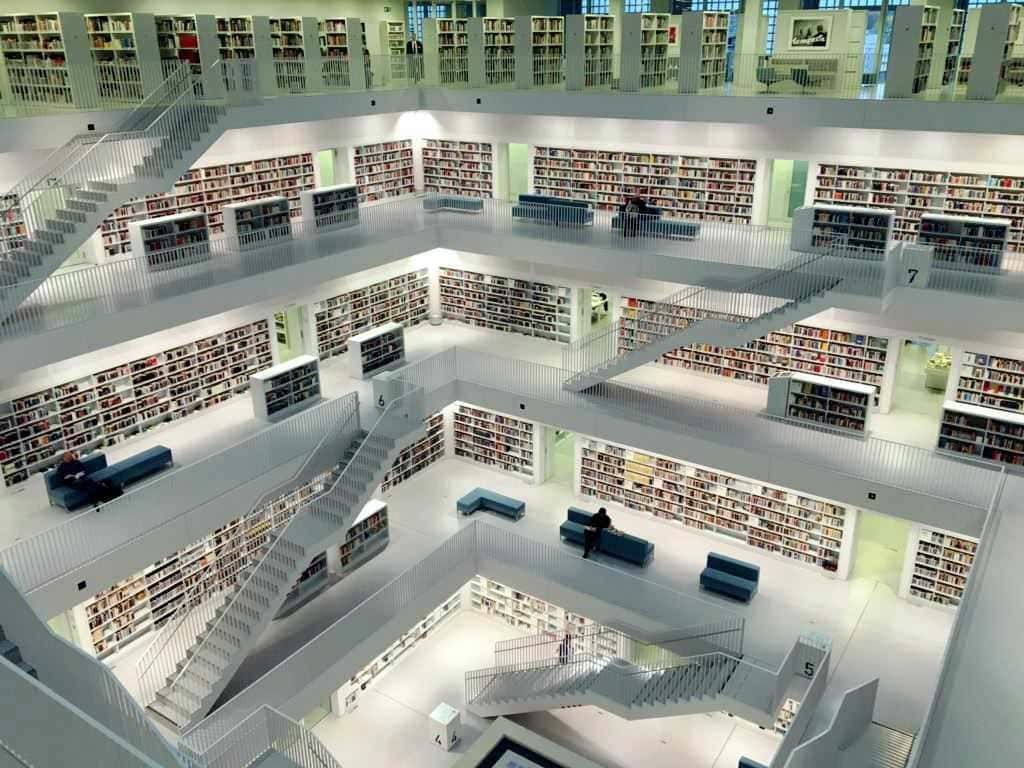 Biblioteca moderna con librerie multilevel e scale, ambienti luminosi e spazi di lettura tranquilli, perfetta per studio e ricerca.