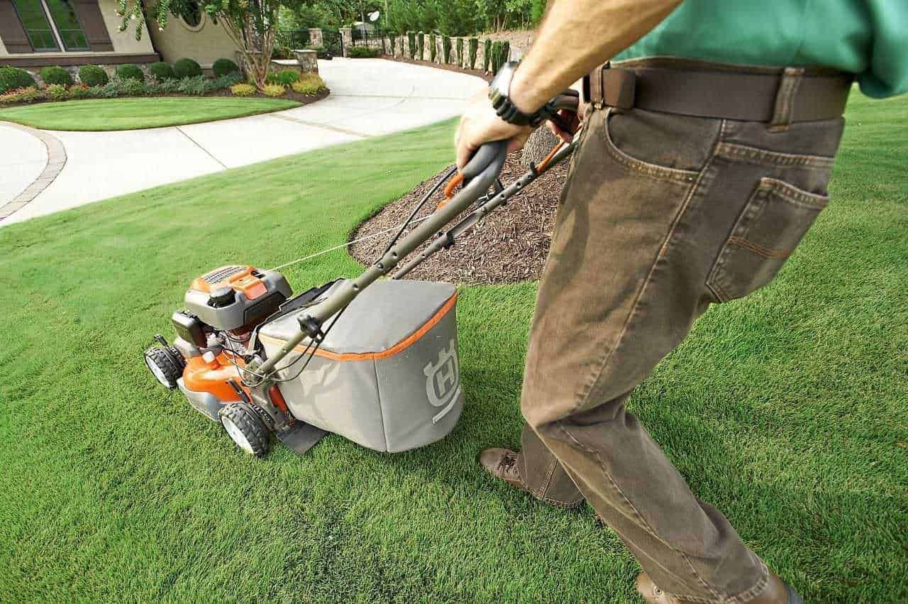 Attrezzi giardinaggio elettrici: Attrezzi elettrici da giardinaggio: Tag alt: Uomo che falcia il prato con tosaerba a motore in giardino, cura il prato verde curato e ben tenuto, manutenzione del giardino, strumenti per curare il verde domestico.
