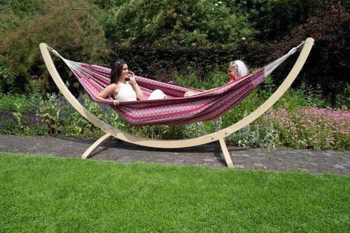 Relaxing in a stylish hammock in a lush garden setting, two women enjoying a peaceful moment outdoors, perfect for leisure and relaxation.