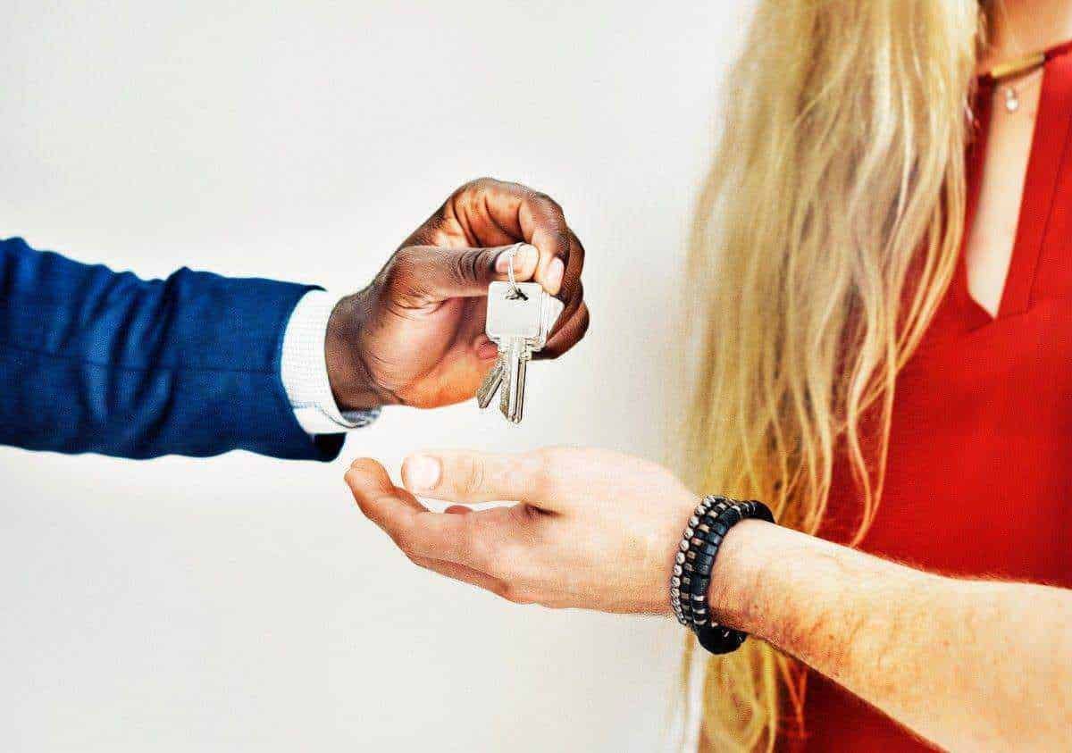 Chiavi in mano consegnate durante una transazione immobiliare o di affitto, simbolo di accordo e fiducia tra due persone, rappresentando il momento di consegna delle chiavi per una nuova casa o proprietà.
