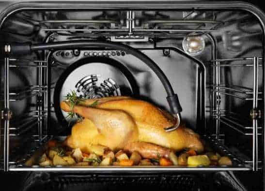Pollo arrosto cotto nel forno con verdure miste, vista dall’interno del forno a microonde.