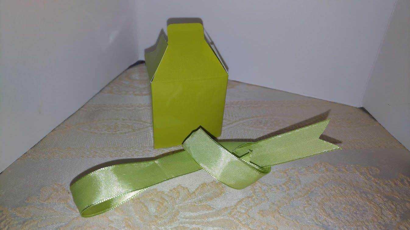 Filem,alt="Fascetta di nastro verde e scatola di cartone in visuale inclinata, oggetto per imballaggio e confezionamento regalo",caption="Fascetta di nastro verde accantivata vicino a una scatola di cartone, ideale per imballaggi e regali, rappresentando materiali di packaging e confezionamento",image_description="L'immagine mostra una fascetta di nastro color verde acceso posizionata vicino a una scatola di cartone. La scena è scattata in un ambiente interno con sfondo bianco e superficie in tessuto. La fascetta di nastro è utilizzata per chiudere o decorare confezioni e regali, sottolineando l'importanza del packaging nel confezionamento di prodotti o doni." ,relevance="Alta, collegata al packaging, imballaggio e confezionamento.".