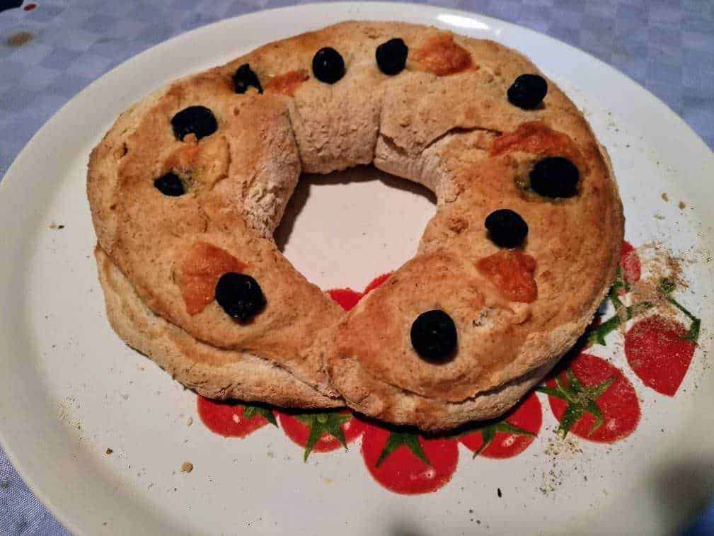 Pane dolce a forma di ciambella con cioccolato e frutta, decorato con cioccolato fondente. Perfetto per colazioni o merende in famiglia, con un aspetto rustico e invitante. Ricetta semplice e gustosa.