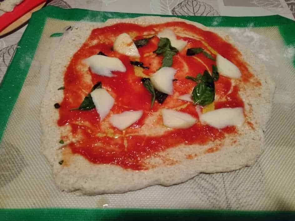 Pomodoro, mozzarella, basilico su pizza margherita fatta in casa, Italia, preparazione pizza, ricetta italiana, ingredienti freschi, cucina casalinga, pietanza tradizionale italiana, food art, impasto pizza.