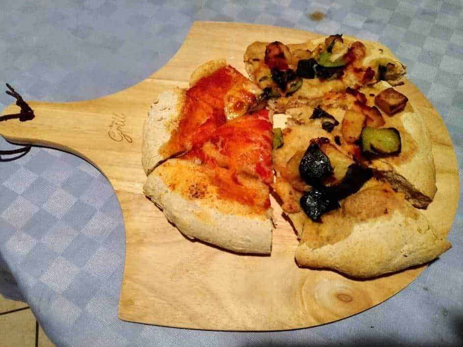 Pietra refrattaria pizzastein: Crosta di pizza con topping di pomodoro e verdure, servita su tagliere di legno.