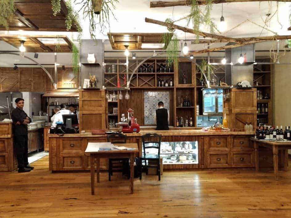 Elegante bar in stile rustico con arredi in legno e luce calda, atmosfera accogliente per aperitivi e cocktail di qualità in un locale trendy di Milano.
