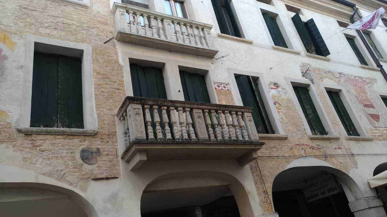 Balcone in stile classico su edificio storico con pietra e mura dipinte, evidenziando architettura tradizionale italiana e dettagli decorativi, ideale per appunti su design edilizio e patrimonio culturale.