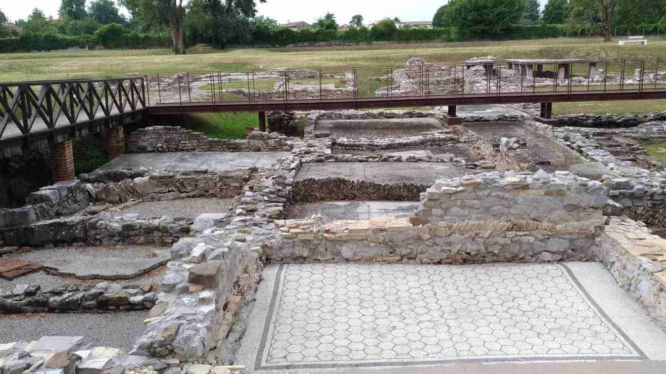 Resti archeologici romani con pavimentazione in mosaico, area di scavi storici e ponte in ferro, sito archeologico a cielo aperto, patrimonio culturale e storico italiano, visite archeologiche pubbliche.