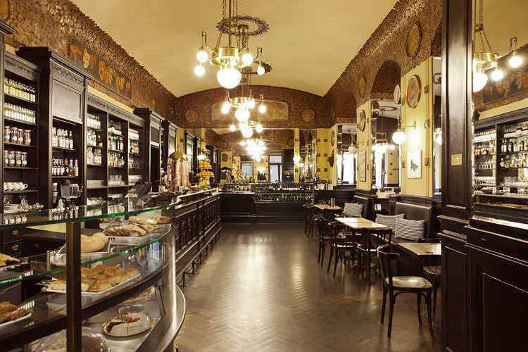 Una sala da tè elegante con arredi classici, scaffali di prodotti da forno e un'atmosfera accogliente, perfetta per gustare deliziosi dolci e tè pregiati in un ambiente raffinato.