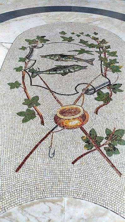 Una rappresentazione artistica di tre pesci raffigurati in mosaico, circondati da foglie di vite, con un'ampia ciotola centrale, perfetta per riviste di arte e design di mosaici.