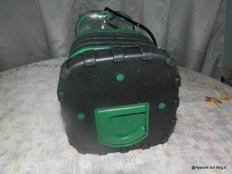 Valigia da viaggio in plastica con ruote color nero e verde, senza maniglia visibile, ideale per trasportare oggetti durante le vacanze o spostamenti.