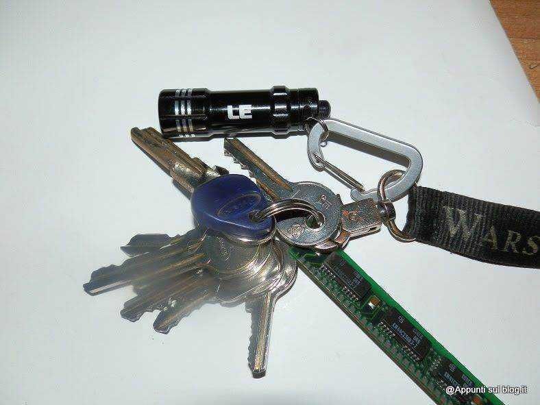 Chiavi, torcia e nastrino da portachiavi su sfondo bianco, oggetti utili per la sicurezza e l'organizzazione quotidiana. Ideali per chi cerca praticità e accessori multimodali.
